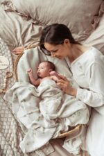 Baby in a wicker basket covered with the Eucalyptus bamboo muslin swaddle, mother beside