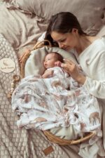 Mother with a baby in a wicker basket covered with the Forest Friends bamboo muslin swaddle