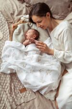 Mother with a baby in a wicker basket covered with the Happy Goose bamboo muslin swaddle