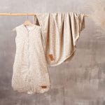 Śpiworek i kocyk Herbs zawieszone na drążku na tle szarej ściany