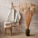 Happy Goose Olive sleeping bag and blanket hanging on a ladder next to dried pampas grass