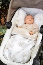 Baby in a pram bassinet covered with the white Happy Goose cotton blanket