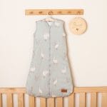 Olive Happy Goose Olive sleeping bag with white geese on a hanger above a cot