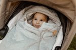 Baby with the hood of the olive Happy Goose Olive footmuff up in a pram