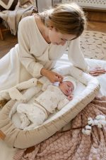 Mother adjusting the hat of a baby sleeping in the Happy Goose baby nest with a goose print