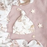 Forest Friends knot baby hat on a pink knitted blanket, printed with bunnies and birds