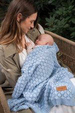 Mama trzyma na rękach śpiące niemowlę otulone kocykiem bambusowym Fema w kolorze baby blue