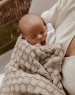 Sleeping newborn wrapped in the Fema bamboo blanket in beige in his mother's arms