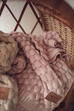 Fema bamboo blanket in misty rose folded in a wicker basket next to a beige one