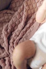 Fema bamboo blanket in misty rose and a baby's leg - close-up of the openwork knit
