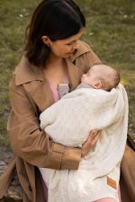 Mama tuli śpiące niemowlę owinięte kocykiem bambusowym Hana w kolorze ciepły beż