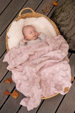 Baby in a wicker basket covered with the Ivi bamboo blanket in dusty pink