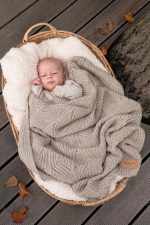 Baby in a wicker basket covered with the Bono merino blanket in cappuccino