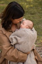 Mother hugging a baby wrapped in the openwork Bono merino blanket in cappuccino