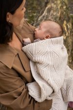 Mother holding a baby wrapped in the Bono merino blanket in warm beige