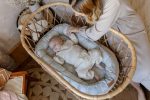 Happy Goose Olive baby nest in a rattan basket with a sleeping baby inside