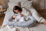 Mother with a baby in the Happy Goose Olive baby nest on a bed in a bright bedroom