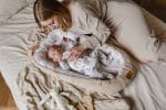 Mama leży przy niemowlęciu w kokonie Forest Friends ułożonym na łóżku