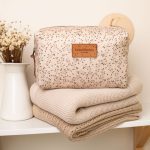 Herbs toiletry bag M on a folded beige blanket on a shelf next to dried flowers