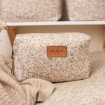 Herbs toiletry bag M with a sprig print on a bed with a knitted blanket