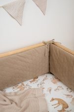 Zbliżenie na pikowanie ochraniacza Velvet w kolorze cappuccino w narożniku łóżeczka