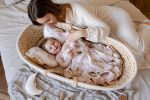 Mama pochyla się nad niemowlęciem w koszu z poduszką Motylek Forest Friends Beige