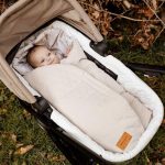 Birdsong swaddle in a pram bassinet with a baby inside