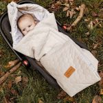 Baby in a car seat wrapped in the quilted Birdsong swaddle