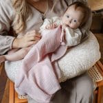 Niemowlę na poduszce do karmienia Herbs przykryte różową pieluszką muślinową