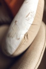 Poduszka do karmienia Happy Goose w gąski oparta o fotel, widoczny suwak