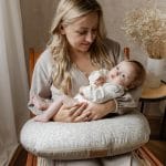 Mama trzyma niemowlę na poduszce do karmienia Herbs w drobne gałązki