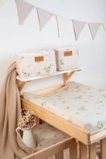 Changing pad in the cream Eucalyptus cover on a cot, with a beige blanket beside it