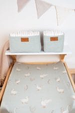Happy Goose Olive changing pad cover with geese, with sage nappy baskets on the shelf