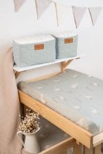 Changing pad in the sage Happy Goose Olive cover on a cot, next to dried flowers
