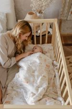 Mama przy łóżeczku z niemowlęciem przykrytym kołdrą Dreamland w akwarelowe zwierzątka