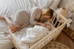 Mama leży przy łóżeczku i czuwa nad niemowlęciem pod kołdrą Dreamland