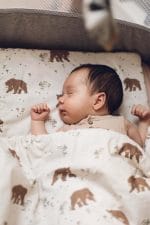 Sleeping baby on the Temo pillow, covered with the brown bear print duvet