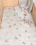 Birdsong fitted sheet with birds and blossom in a cot with a blanket and soft toy