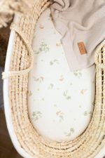 Eucalyptus fitted sheet in a wicker Moses basket with a beige blanket and leather tag