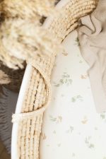 Close-up of the eucalyptus leaf pattern on a fitted sheet in a Moses basket