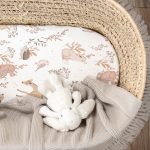 Forest Friends fitted sheet in a basket with a beige blanket and a plush bunny