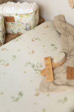 Eucalyptus changing pad cover with a wooden brush and a nappy basket in the background