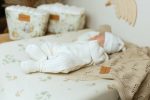 Baby in white clothes lying on a changing pad with the Eucalyptus cover
