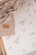Close-up of the Eucalyptus cover with a green and rust leaf print and a knitted blanket