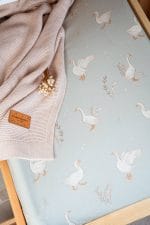 Close-up of white geese on the sage Happy Goose Olive cover, with a beige blanket