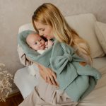 Mama tuli niemowlę owinięte oliwkowym rożkiem muślinowym