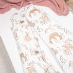 Unzipped Forest Friends sleeping bag with deer and bunnies on a bed with a pink blanket