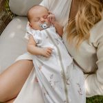Sleeping baby with a dummy in the Happy Goose sleeping bag held by mother