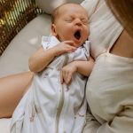 Yawning baby in the Happy Goose 0.5 TOG sleeping bag in mother's arms
