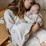 Mama tuli śpiącego noworodka w śpiworku Eucalyptus w listki eukaliptusa